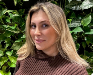 a woman smiling in front of a plant